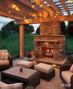 an outdoor fireplace and seating area with lights