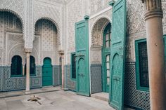 the interior of an ornate building with green doors and arches on either side of it