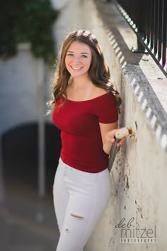 a beautiful young woman leaning against a wall