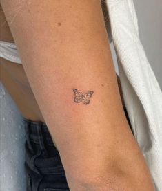 a woman's arm with a small butterfly tattoo on the left side of her arm