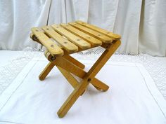 a small wooden stool sitting on top of a white tablecloth covered floor next to a curtain