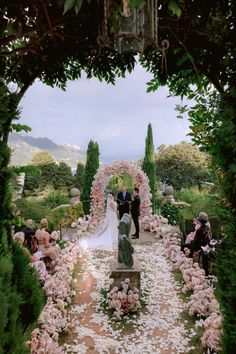 a bride and groom walking down the aisle at their wedding ceremony in an italian garden