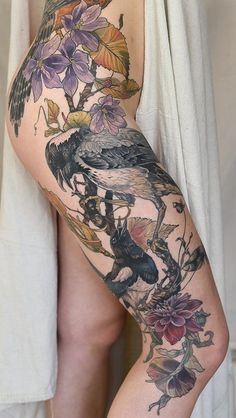 a woman's leg with tattoos on it and flowers in the bottom part of her thigh