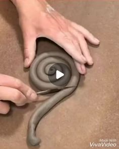 someone is making a snake out of clay with their hands and thumbnails on it