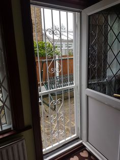 an open door leading to a patio with a bench in the back ground and fenced yard behind it