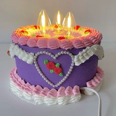 a purple cake with pink icing and hearts on it has candles in the shape of a heart