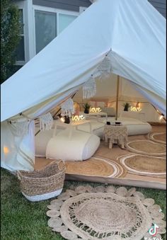 a white tent sitting on top of a grass covered field next to a rug and wicker basket