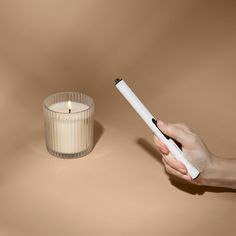 a person holding a pen next to a candle