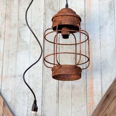 an old rusty light fixture hanging from a wooden plank wall with a wire attached to it