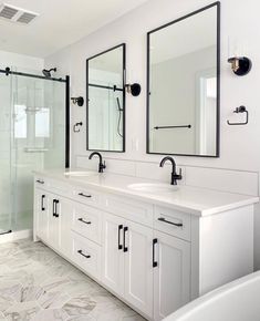 a white bathroom with double sinks and mirrors