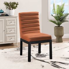 a brown chair sitting on top of a white rug next to a potted plant