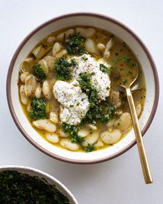 a white bowl filled with pasta and broccoli next to a bowl of pesto