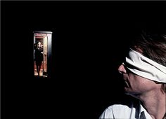 a man with blindfolded head standing in front of an open door