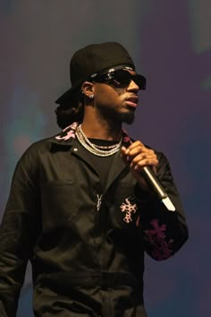 a man holding a microphone in his right hand and wearing sunglasses on top of him