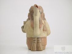 an old ceramic figurine is sitting on a white surface with the head turned to look like it's holding something in its hands