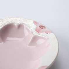 a white plate with a pink flower on the rim and an empty bowl next to it