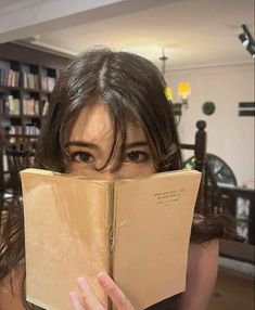 a woman holding an open book in front of her face