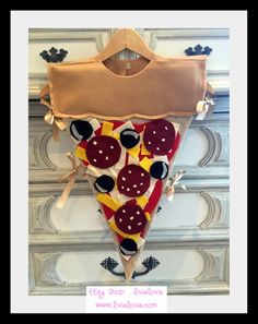 a piece of pizza hanging on the wall with buttons and bows attached to it's side