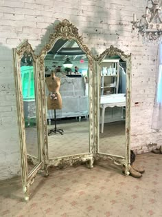 an ornately decorated three - sided mirror in front of a white brick wall with a dress on it