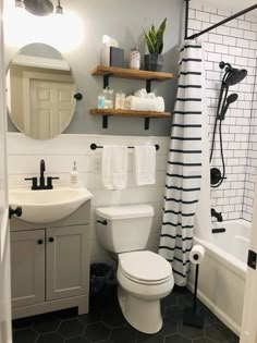 a white toilet sitting next to a bath tub under a bathroom mirror above a sink