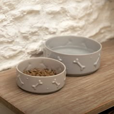 two bowls with dog food in them sitting on a table