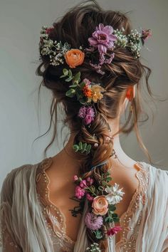 a woman with flowers in her hair is wearing a white dress and has an intricate braid