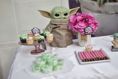 a table topped with cupcakes and baby yoda figurines on top of a white table cloth