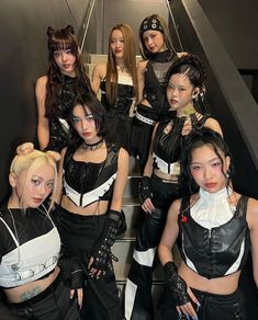 a group of young women dressed in black and white outfits posing for a photo on an escalator