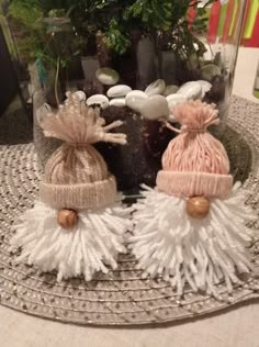 two knitted hats sitting on top of a glass container filled with rocks and plants