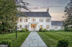 a large white house sitting on top of a lush green field