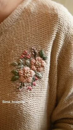 a close up of a person wearing a sweater with flowers on it