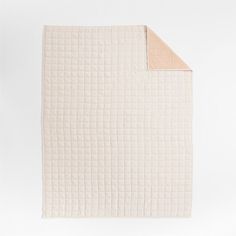 an unmade quilted blanket on top of a white tablecloth with a tan edge