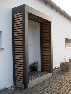 an open door on the side of a white building with wooden slatted shutters