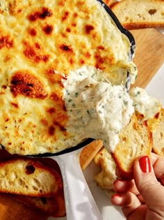 a hand holding a piece of bread with cheese on it and dip in the middle