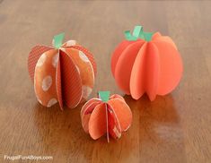 two paper pumpkins sitting on top of a wooden table