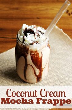 a glass jar filled with ice cream and whipped cream on top of a napkin next to a spoon