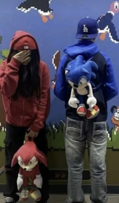 two people standing next to each other in front of a wall with cartoon characters on it