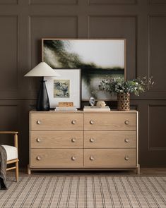 a room with a dresser, lamp and pictures on the wall