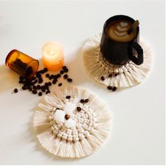 two coasters with coffee beans on them next to a candle and some other items