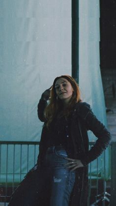 a woman standing in front of a white curtain with her hands on her head and looking at the camera