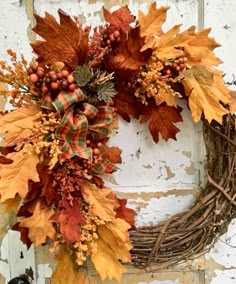 a wreath with leaves and berries hanging on a white door frame, ready to be decorated for the fall season