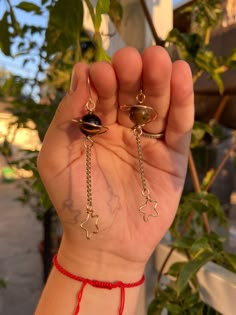 a person is holding up their hand with two rings on it and some beads hanging from them