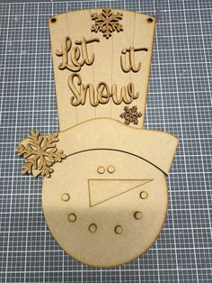 a wooden snowman ornament with let it snow written on the front and bottom