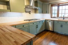 an empty kitchen with wooden counter tops and green cabinets, along with a dishwasher