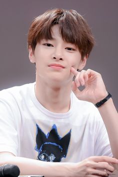 a young man sitting at a table with his hand on his chin