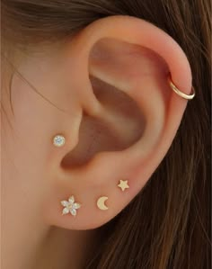 a woman wearing three different ear piercings with stars, moon and crescent designs on them