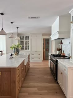 a large kitchen with white cabinets and wood floors