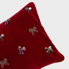 a red pillow with bows and sequins on it