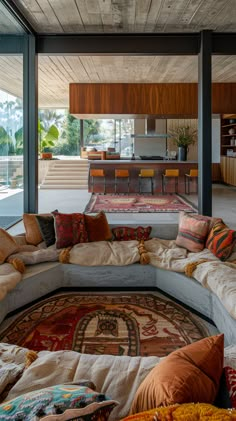 a living room filled with lots of furniture and pillows on top of a large rug