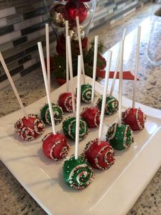 there are many candy lollipops on the white plate with red and green candies